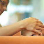 Mutter hat eine Hand auf Kindes Kopf. Kind schaut mit einem Auge über Couchrand ©Ernst Vikne http://www.flickr.com/people/iboy/